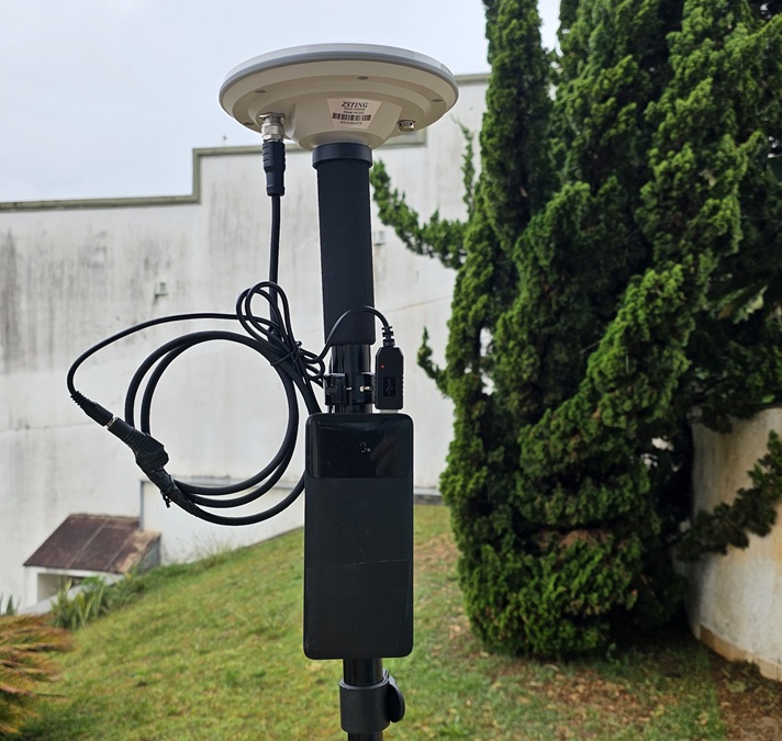 Antena AK330 montada no topo de um bastão, com o cabo de alimentação ligado a um power bank preso ao bastão