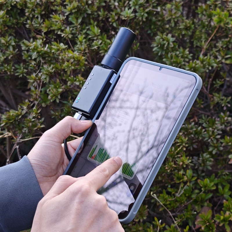 Receptor DATAGNSS NANO RTK Pro, com antena, preso às costas de um celular
